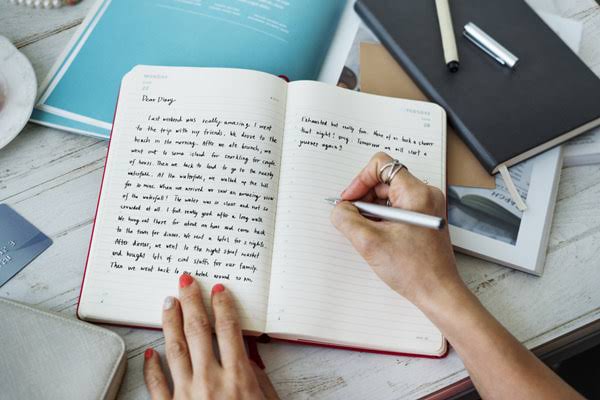 A person writing in their diary about their experiences from the day.